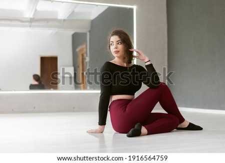 Attractive woman gymnast or dancer exercising doing gymnastic exercises indoors in dance studio