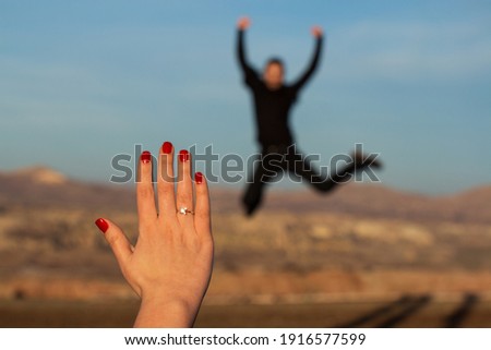 She said yes to marriage proposal, closeup marriage diamond ring and woman's hand. Jumping happy man in the blurred background. Selective focus, blurred areas. Royalty-Free Stock Photo #1916577599