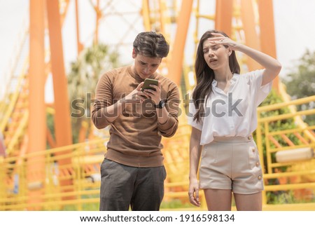 couple of man and woman using phone finding a map to go at outdoor public amusement park. people meeting for activity of love and enjoy lifestyle of dating and traveling.