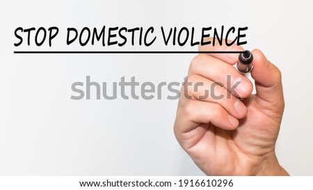 the hand writes text STOP DOMESTIC VIOLENCE with a marker on a white background. business concept
