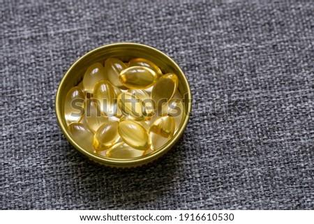 Gelatin capsules in a cork made of gold-colored metal on a background of gray fabric. Macro. 