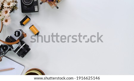 Top view of photographer workplace with camera, film, notebook and copy space on white table.