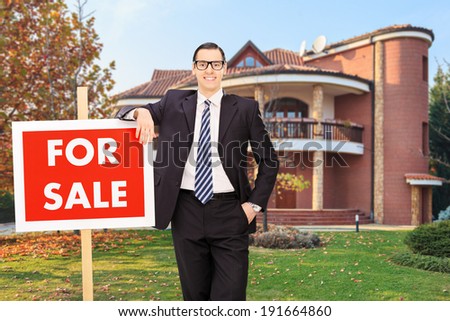 Realtor advertising a house for sale standing in the front yard outside