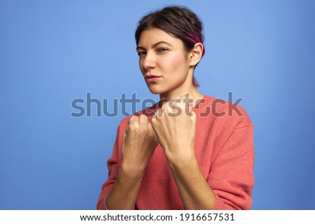 Disturbed confident girl expressing anger, rage or aggression, clenching fist, having outraged look, warning about revenge, ready to punch enemy, protecting herself against domestic violence or abuse Royalty-Free Stock Photo #1916657531