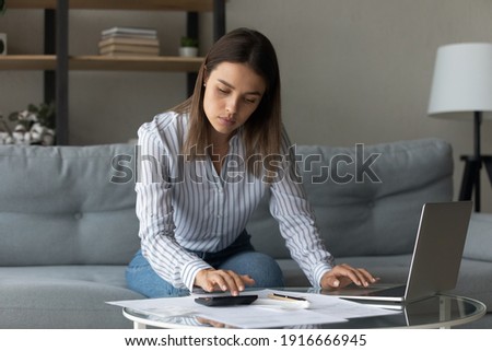 Time to pay bills. Concentrated woman pay domestic utilities at online app calculate fee work with financial papers. Young lady owner renter tenant of house flat engaged in housekeeping at home office Royalty-Free Stock Photo #1916666945