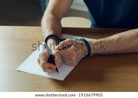 Men hands with handcuffs fill the police record, confession. on top of the police investigative detective. Arrest, bail, criminal, prison. fingerprints, criminal Royalty-Free Stock Photo #1916679905