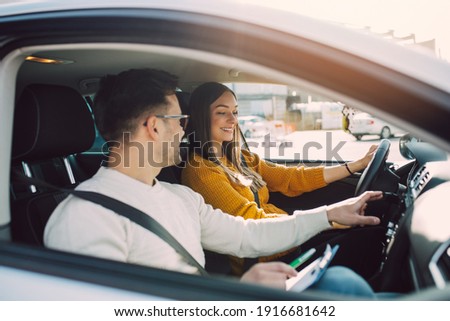 Driving school or test. Beautiful young pregnant woman learning how to drive car together with her instructor.  Royalty-Free Stock Photo #1916681642