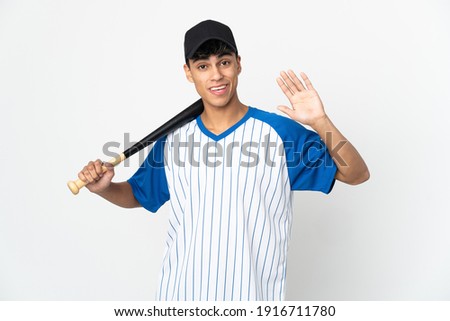 Man playing baseball over isolated white background saluting with hand with happy expression