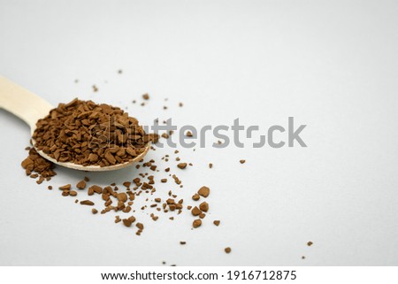 A wooden spoon with instant coffee on the table. Light background. Coffee scattered around. No waste concept. Space for the text on the right. Royalty-Free Stock Photo #1916712875