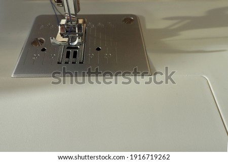 the leg and needle of a white sewing machine top view