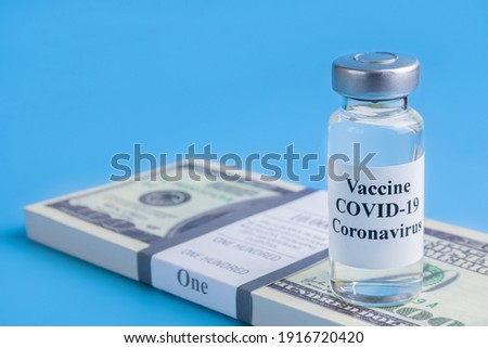 omicron variant, ampoule with vaccine against the virus on pack of hundred-dollar bills on blue background, concept of the pharmacological business, coronavirus, SARS-CoV-2, closeup