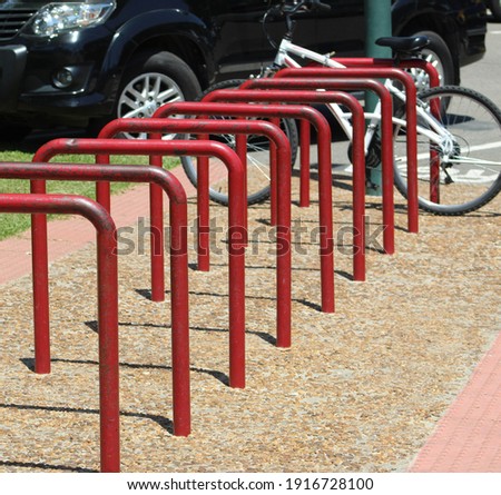 red iron support for placing upright bikes, protected on the sidewalk