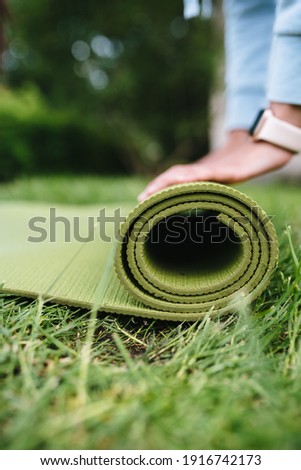 Close-up of woman folding roll fitness after working out in the park
