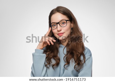 A teenage woman with long hair and glasses. The girl is wearing a light blue oversized sweatshirt. Royalty-Free Stock Photo #1916751173