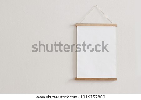 Blank wooden picture frame hanging on beige wall. Empty poster mockup for art display. Minimal interior design.Front view, copy space. No people. 