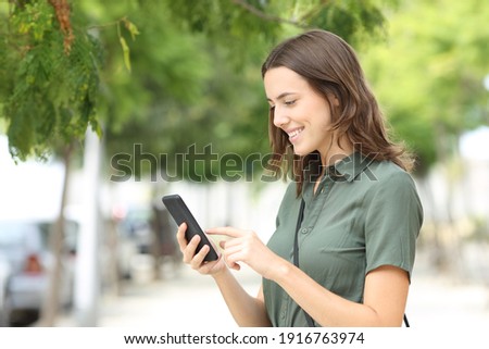 Happy woman walking using smart phone in a city street