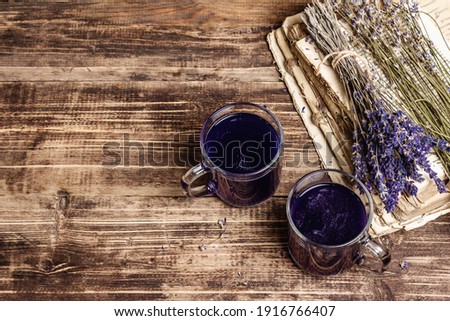 Lavender hot tea on vintage wooden table. Natural organic flower drink for morning good mood, old books, dry bouquet, top view