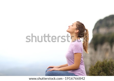 Side view portrait of a woman sitting breathing fresh air in the mountain Royalty-Free Stock Photo #1916766842