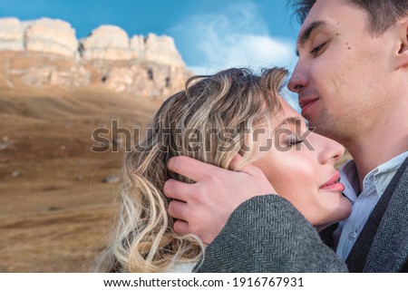 Beautiful young couple hugs high in the mountains in autumn. Relationship, travel and tourism concept