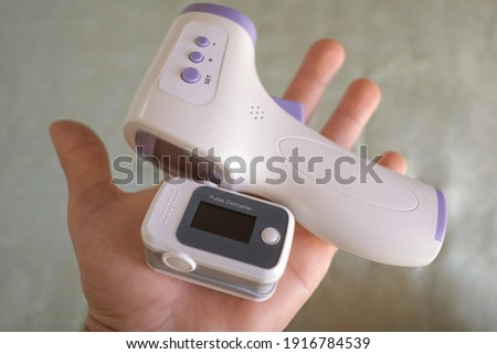 Man hold pulse oximeter and digital fever thermometer,oxygen saturation in covid19 pandemic disease,medical home monitoring treatment