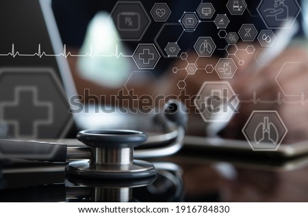 Medical technology, online health, telemedicine concept. Doctor working on digital tablet and laptop computer, electronic health record in hospital with icons on virtual screen