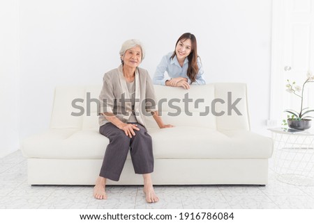 close up old Asian female sitting on sofa, young asian female rest hand on sofa, they feeling happy and smile in relax time, mother's day, happiness elderly in family time
