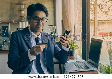 Front Right Smile Asian Businessman in Suit Wear Glasses Using Smartphone for Online Shopping in Coffee Shop Scene. Asian Businessman Work from Anywhere with Technology in Vintage Tone