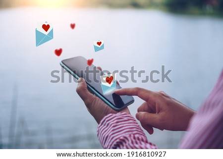 Hand typing love letter email in smartphone social network online community  with social media love letter mail send out icons valentine concept.