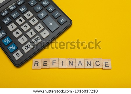 Phrase or word - refinance. Wooden block letter word and modern calculator on a yellow background, business concept with space for text