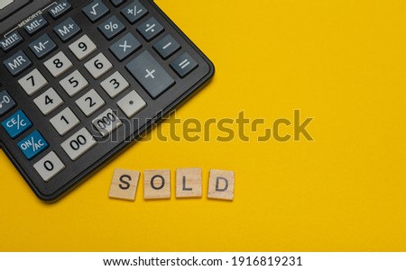 Phrase or word - sold. Wooden block letter word and modern calculator on a yellow background, business concept with space for text