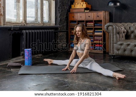 Young pretty woman in a sport suit doing stretching exercises at home. Sports during a pandemic on isolation, online gymnastics and yoga classes. Healthy lifestyle. High quality photo
