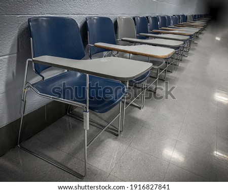 Moody, Angled Shot of a Row of School Chairs against a Wall, Extending to a Shadowy Background Royalty-Free Stock Photo #1916827841
