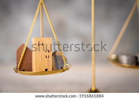 Wood house and Coins stack with balance scale. Money management, financial plan, time value of money. Real estate and property agent offer house concepts.