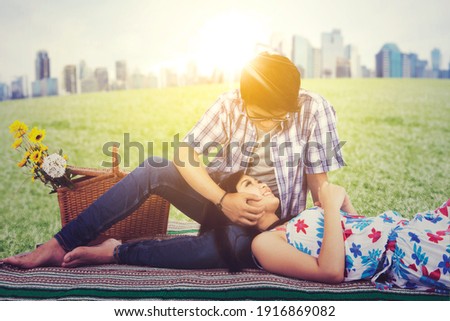 Picture of romantic young couple enjoying leisure time together while dating at the park with modern city background
