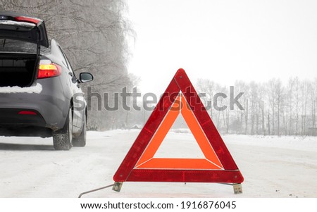 Emergency red sign on a snow-covered road.Car breakdown on the highway. The concept of road safety.