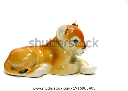 Antiques, art, collectibles. Swap meet. Isolated over white background. figurine of a tiger lying on the floor, glazed ceramics