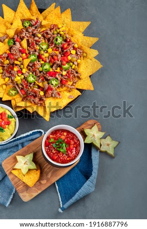Delicious hispanic mexican meal board with nachos, beef, guacamole, avocado and starfruit. Hot and spicy. Top view, copy space