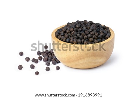 Closeup black pepper seeds or peppercorns (dried seeds of piper nigrum) in wooden bowl isolated on white background. Royalty-Free Stock Photo #1916893991
