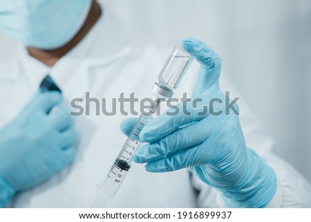 A doctor or scientist in the COVID-19 medical vaccine research and development laboratory holds a syringe with a liquid vaccine to study and analyze antibody samples for the patient.
 Royalty-Free Stock Photo #1916899937