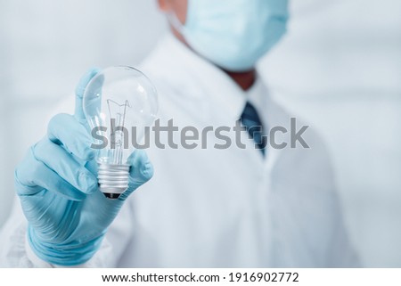 A doctor or scientist in a research laboratory Holding a light bulb that conveys research into the concept of virus protection
