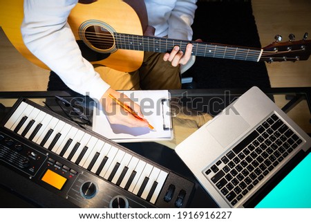 top view of male songwriter writing a song with laptop computer and keyboard on desk. songwriting concept Royalty-Free Stock Photo #1916916227