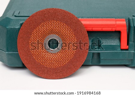 Abrasive black wheel, grinding wheel on the background of the green toolbox. Abrasive materials, discs, tools close-up