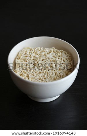 Instant Noodles in ceramic bowl on dark background with natural light. Raw noodles in the bowl.