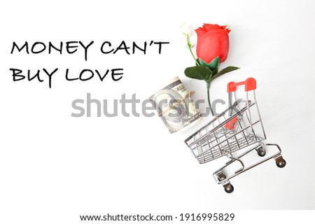Top view of shopping cart , flower and money banknote over white background written with text MONEY CAN'T BUY LOVE.