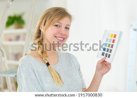 happy woman choosing paint colour from swatch for new home
