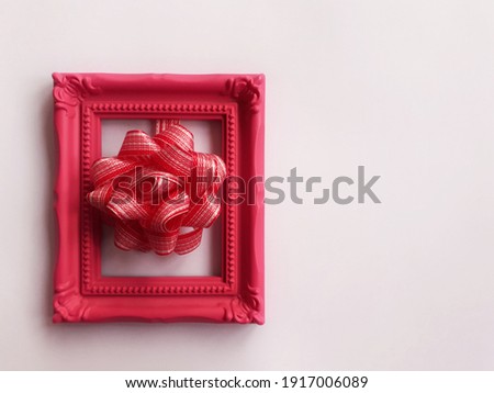 Minimal copy space for Christmas, New year and holiday season. Pink frame with red ribbon bow on white background. Empty space for text. Flat lay.