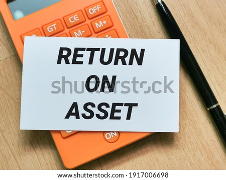 Business and finance concept. Phrase RETURN ON ASSET written on white card with pen and calculator.
