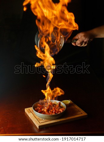 Hot dish cooked on fire with fire in the frame black background