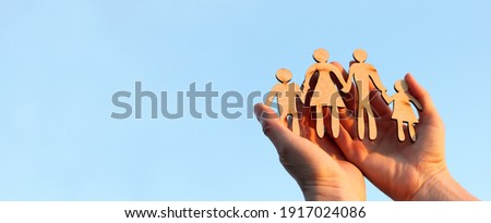 wooden silhouette of a man and a woman with two children in their arms against a background of blue sky. warm family relationships