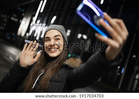 A beautiful girl waving at a smartphone camera